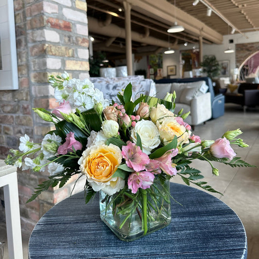 Day Light floral arrangement by Birch & Blossom featuring David Austin roses, white stock, pink alstroemeria, pink lisianthus, white Eskimo roses, pink hypericum, leather leaf, aspidistra, and ruscus in a glass cube vase. Soft, romantic, and elegant.